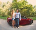 Young happy couple standing near red car Royalty Free Stock Photo