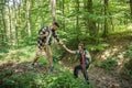 Young happy couple and their dog at hiking through the woods enjoying the sight. Two nature lovers in the mountain forest enjoy he Royalty Free Stock Photo