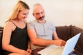 Young happy couple using laptop in couch and enjoy at home. Royalty Free Stock Photo