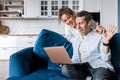 Young happy couple using laptop talking online with friends and family at home, smiling husband and wife millennial Royalty Free Stock Photo