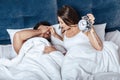 Young happy couple waking up with alarm clock in bed Royalty Free Stock Photo