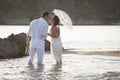 Young happy couple walking along beach rocks at sunrise Royalty Free Stock Photo