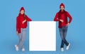 Young Happy Couple Wearing Winter Hats Leaning At White Advertisement Board Royalty Free Stock Photo