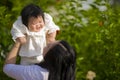 Young happy and cute Asian Chinese woman enjoying and playing with her baby girl daughter holding her raising up in her arms Royalty Free Stock Photo