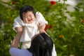 Young happy and cute Asian Chinese woman enjoying and playing with her baby girl daughter holding her raising up in her arms Royalty Free Stock Photo