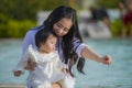 Young happy and cute Asian Japanese woman playing with daughter baby girl at holidays tropical resort swimming pool enjoying