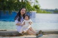 Young happy and cute Asian Korean woman playing with daughter baby girl at holidays tropical resort swimming pool enjoying summer