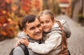 Young happy dad and little daughter hugging in autumn park. Family time, togehterness, parenting and happy childhood concept.