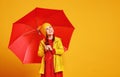 Happy emotional cheerful child girl laughing with red umbrella on colored yellow background