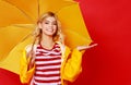 happy emotional cheerful girl laughing and jumping with yellow umbrella on colored red background