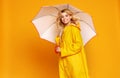 Young happy emotional girl laughing with umbrella on colored yellow background