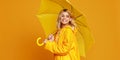 Young happy emotional girl laughing with umbrella on colored yellow background