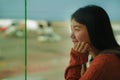 Young happy and excited Asian Chinese student woman with backpack at airport departure lounge watching aircraft through glass Royalty Free Stock Photo