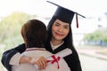 Young happy excited Asian woman university graduates in graduation gown and cap with a degree certificate hugs a friend to Royalty Free Stock Photo