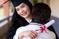 Young happy excited Asian woman university graduates in graduation gown and cap with a degree certificate hugs a friend to Royalty Free Stock Photo