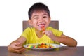 Young happy and excited male kid smiling cheerful eating dish full of candy and lollipop sitting at table isolated on white Royalty Free Stock Photo