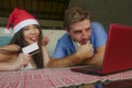 Young happy and excited mixed ethnicity couple with Asian Chinese woman in Christmas hat and Caucasian husband online shopping x-m Royalty Free Stock Photo