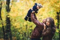 Young happy family in autumn in park. Father joyfully throws his son up. Royalty Free Stock Photo