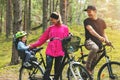 Happy family biking in park with kid in bike child seat. active sports outdoor recreation