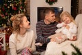 Young happy family celebrates Christmas by the fireplace and Christmas tree