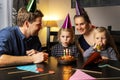 Happy family celebrating daughter birthday at home. girl blowing out the candles on her cake Royalty Free Stock Photo