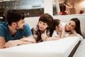 Young happy family checks on softness of orthopedic mattress, lying on bed in furniture store. Royalty Free Stock Photo
