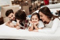 Young happy family checks on softness of orthopedic mattress, lying on bed in furniture store. Royalty Free Stock Photo