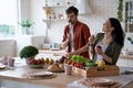 Young happy family couple dancing, singing and having fun while preparing healthy food in the modern kitchen at home Royalty Free Stock Photo