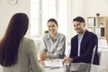 Young smiling family couple meeting with bank worker to sign loan contract