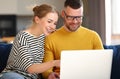 Young happy family couple using laptop while sitting on sofa at home Royalty Free Stock Photo