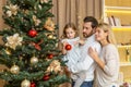 A young happy family decorates a Christmas tree for the Christmas holidays Royalty Free Stock Photo