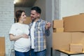 Young happy family expecting a baby. Pregnant woman and husband moved to a new house, apartment. Unpack boxes with things. Hugging Royalty Free Stock Photo