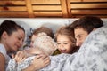 A young happy family is laying tucked in the bed at home together. Family, together, love, home