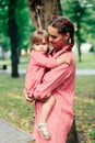 Young happy family with little beautiful baby with blue eyes walking in summer park at sunset. Mom and little daughter Royalty Free Stock Photo