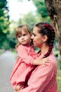 Young happy family with little beautiful baby with blue eyes walking in summer park at sunset. Mom and little daughter Royalty Free Stock Photo