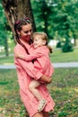 Young happy family with little beautiful baby with blue eyes walking in summer park at sunset. Mom and little daughter Royalty Free Stock Photo