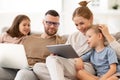 Young family addicted with gadgets relaxing on sofa at home Royalty Free Stock Photo