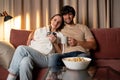 Young happy family, sitting at home on the couch and watching TV, eating popcorn Royalty Free Stock Photo