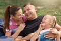 Young happy family spending free time in park on picnic, mother and father laugh from doughter`s joke, they dressed casually, hav Royalty Free Stock Photo