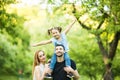 Young happy family of three having fun together outdoor. Pretty little daughter on her father back. Family fun outside. Royalty Free Stock Photo