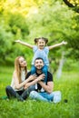 Young happy family of three having fun together outdoor. Pretty little daughter on her father back with happy raised hands. Parent Royalty Free Stock Photo