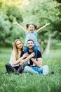 Young happy family of three having fun together outdoor. Pretty little daughter on her father back with happy raised hands. Parent Royalty Free Stock Photo