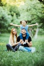 Young happy family of three having fun together outdoor. Pretty little daughter on her father back with happy raised hands. Parent Royalty Free Stock Photo