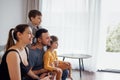 Young happy family with two children is watching television. Relaxed smiling people and cute kids spend time at home Royalty Free Stock Photo