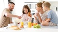 Young happy family with two cute little kids having breakfast together in kitchen and smiling Royalty Free Stock Photo