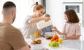 Young happy family with two cute little kids having breakfast together in kitchen and smiling Royalty Free Stock Photo