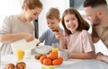 Young happy family with two cute little kids having breakfast together in kitchen and smiling Royalty Free Stock Photo