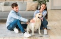 Young happy family of two sitting on floor with dog Royalty Free Stock Photo