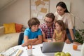 Young happy family working on laptop together, parents helping children with homework or studying online at home during Royalty Free Stock Photo