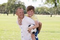 Young happy father carrying on his back excited 7 or 8 years old son playing together soccer football on city park garden posing s